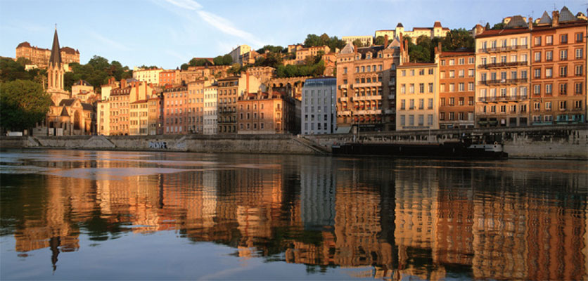 Image of the city of Lyon. One of the rivers is in the foreground and buildings are in the background.