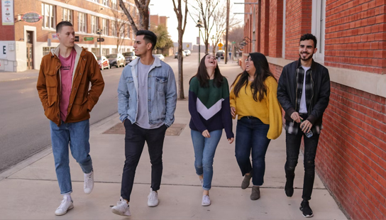 two students looking at an iphone and a tablet.